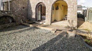 A stone building with a gravel driveway and a small patio area. - The Chalet (Tyn-y-Gongl)