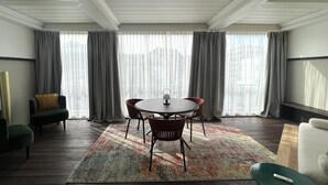 A modern room with a round table, two chairs, a sofa, and a large window with curtains. - Boutique Hotel Martini 17 (Milan)