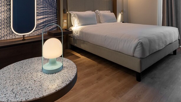 A modern hotel room with a large bed, a round table, a unique wall design, and a ceiling light fixture. - Boutique Hotel Martini 17 (Milan)