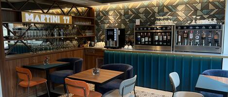 Un espace bar agrémenté d’une enseigne « Martini », de tabourets et d’un présentoir à vins.