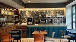 A bar area with a counter, wine bottles, and glasses. There are tables and chairs in the foreground. - Boutique Hotel Martini 17 (Milan)