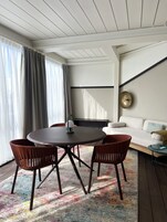 A modern living room with a round table, two chairs, a sofa, and a coffee table.