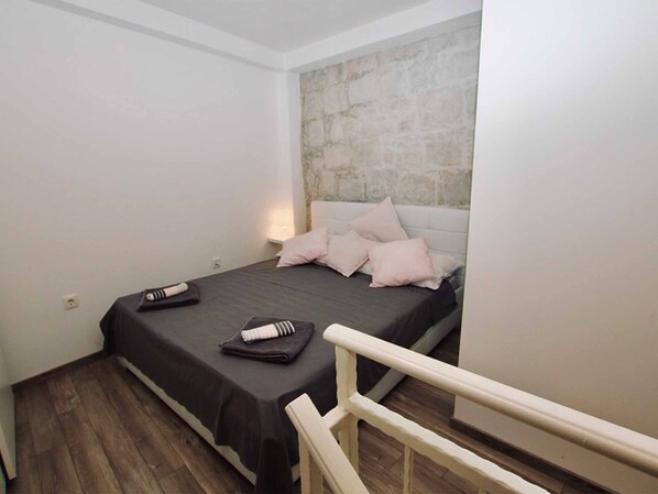 Un dormitorio pequeño y moderno con cama, mesita de noche y una pared de acento de piedra.