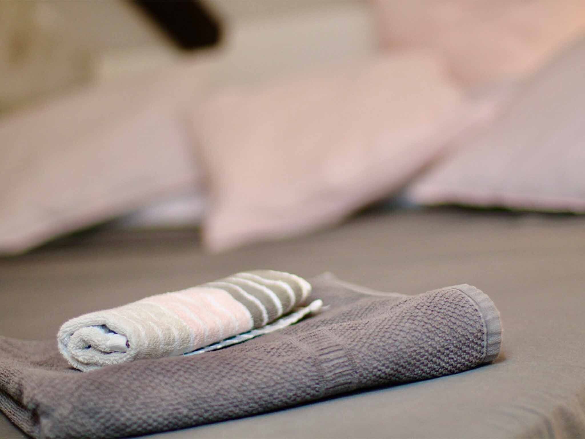 A neatly made bed with a folded towel and a blanket.
