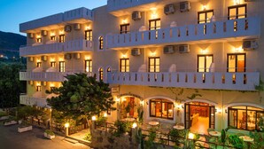 A multi-story hotel with balconies, outdoor seating, and a stone facade. - Floral Hotel (Hersonissos)