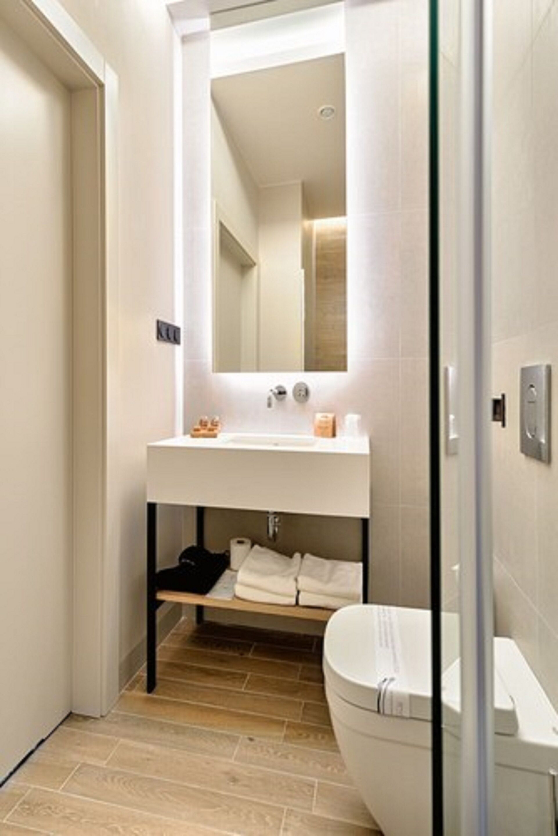 A modern bathroom with a white sink, mirror, and toilet.