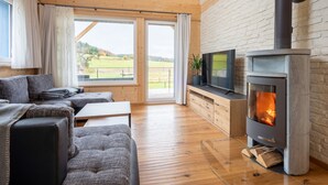 Ein gemütliches Wohnzimmer mit Kamin, bequemen Sitzgelegenheiten und einem Fernseher.