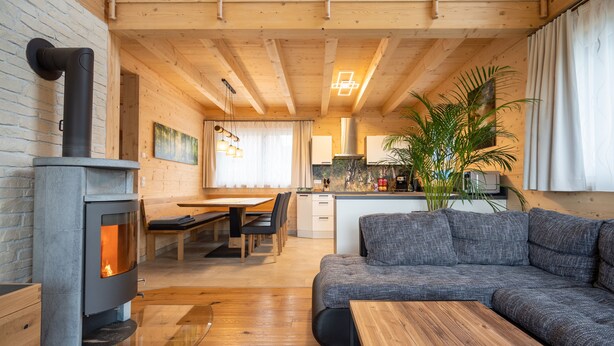 Ein gemütliches Wohnzimmer mit Kamin, einer Couch, einem Essbereich mit Tisch und Stühlen sowie einer Küche im Hintergrund.