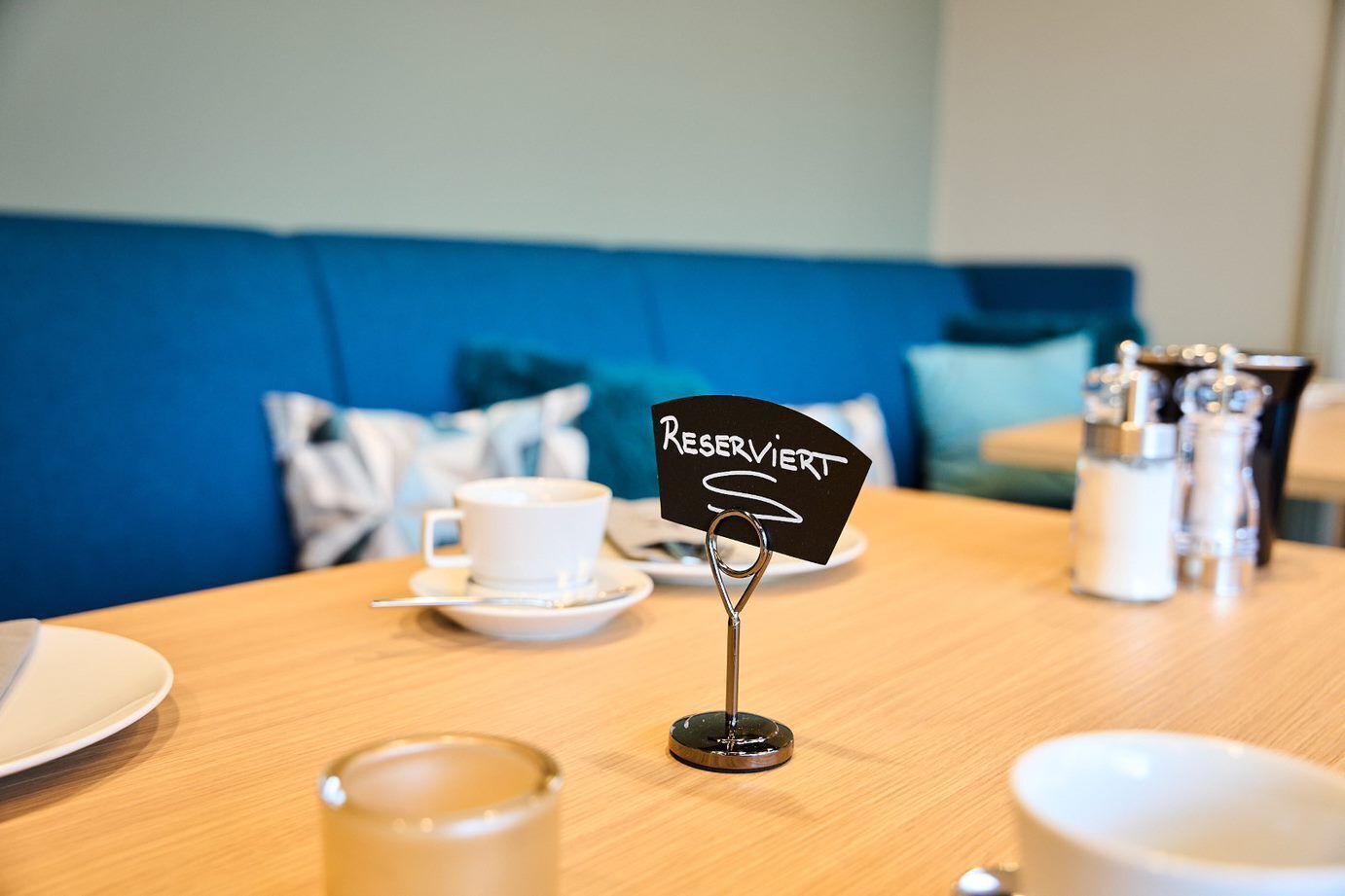Una mesa con un cartel que dice 'RESERVIERT', una taza blanca y saleros y pimenteros.