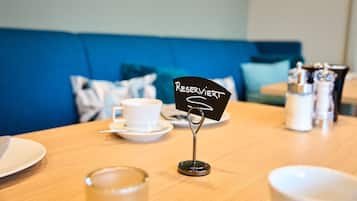 Una mesa con un cartel que dice 'RESERVIERT', una taza blanca y saleros y pimenteros.