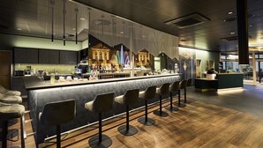 Un espace bar moderne avec un long comptoir, des tabourets de bar et un mur décoratif.