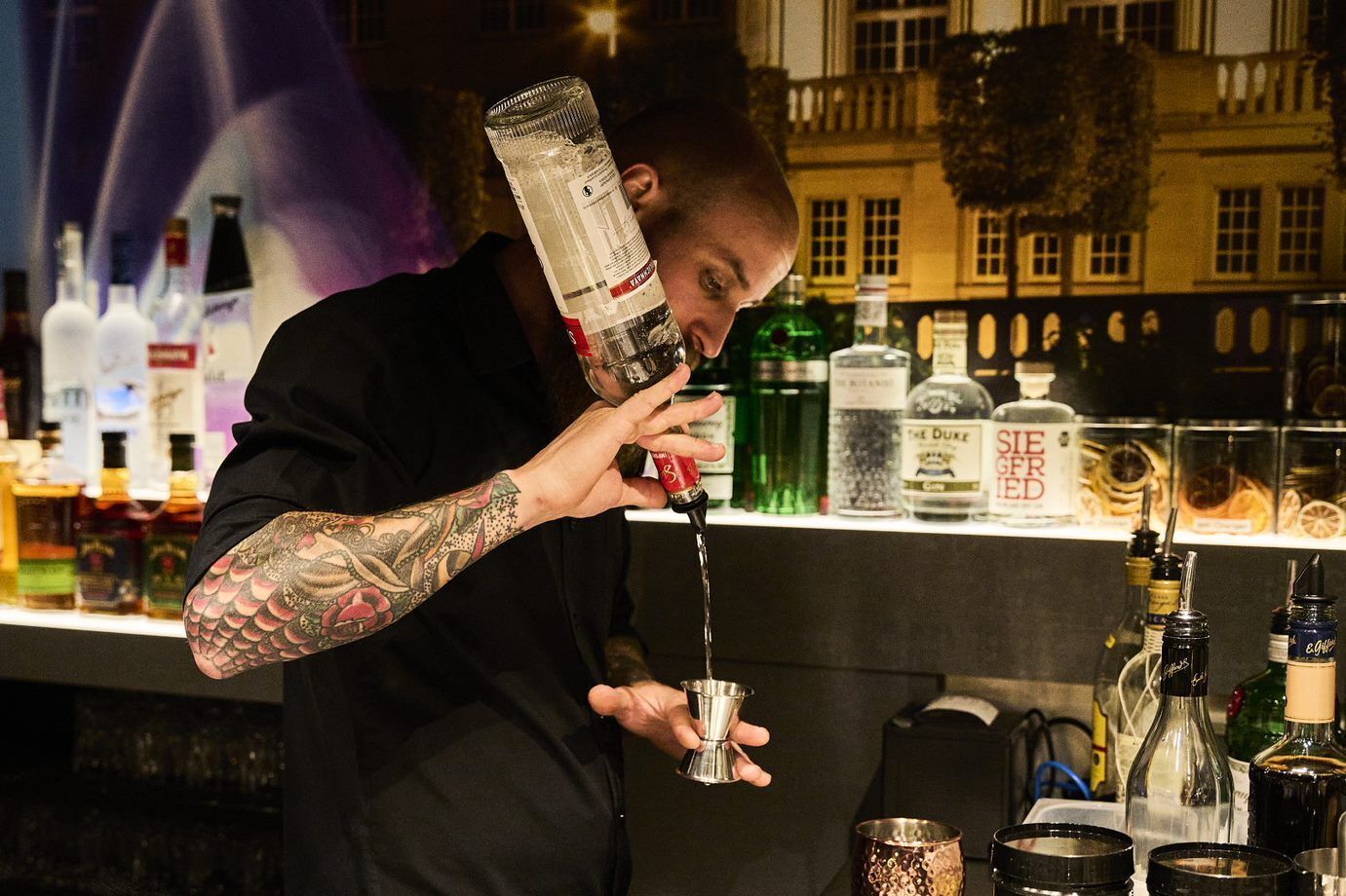 A bartender pouring a drink into a glass.