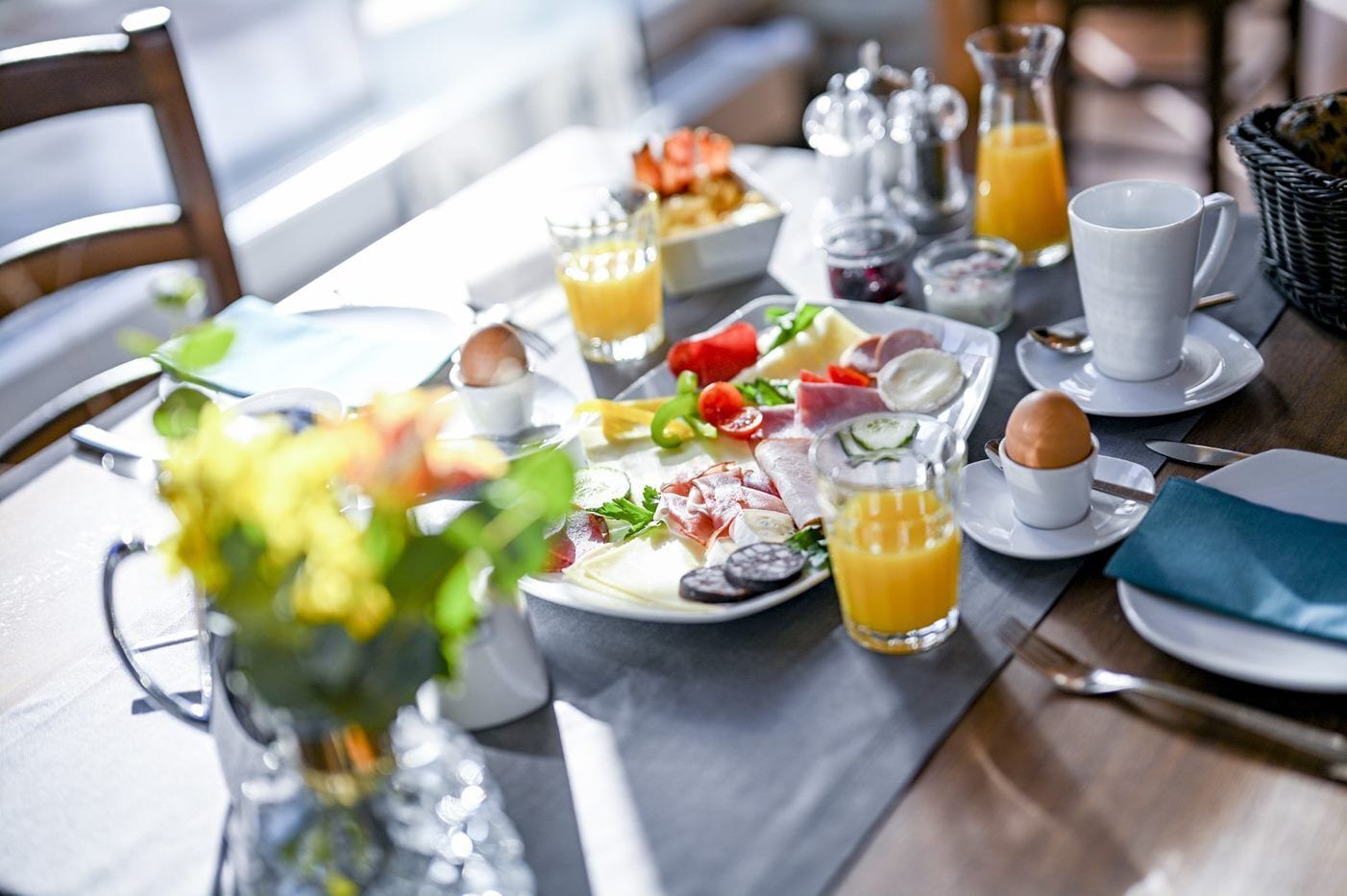 Une table dressée pour le petit-déjeuner, avec une variété de plats, de boissons et de couverts.