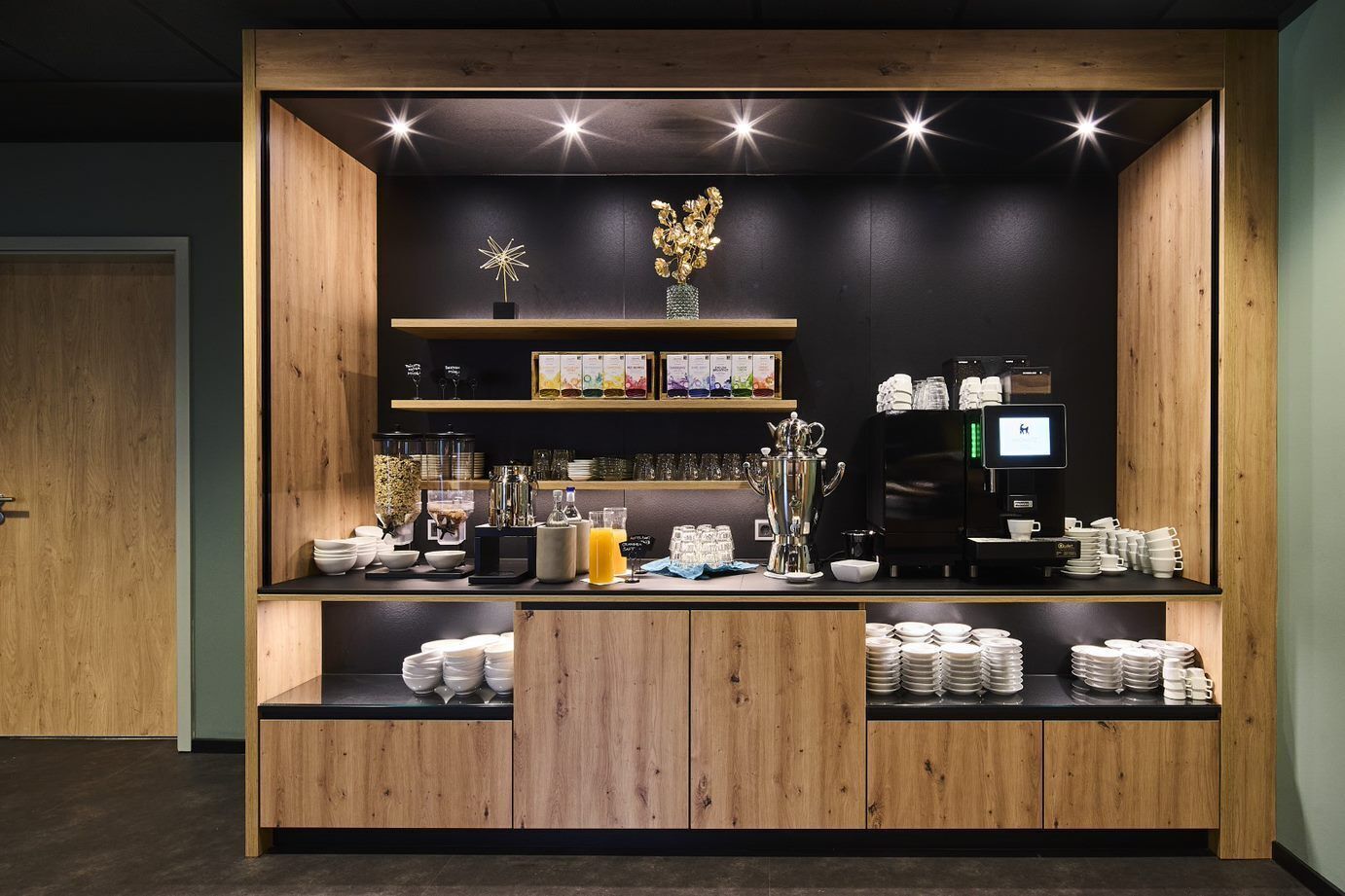 A coffee station with a coffee machine, cups, and a display of coffee beans.