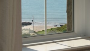 A window view of a beach with rocks and vegetation. - Rosemary Cottage - Three Bedroom House, Sleeps 5 (Mortehoe)