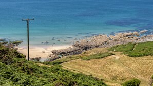 A coastal landscape with rocky terrain, a sandy beach, and a clear view of the sea. - Rosemary Cottage - Three Bedroom House, Sleeps 5 (Mortehoe)