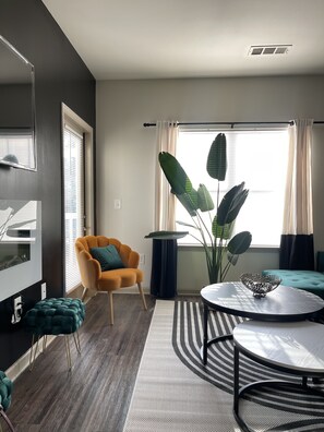 Relax in this stylish living room with a large window, comfortable armchair, and flat-screen TV.