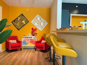 Relax in this stylish living room with a vibrant accent wall, comfortable armchairs, and a decorative wall piece.