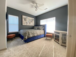 Relax in this serene bedroom with a large bed, ceiling fan, and window with blinds.