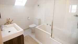 A modern bathroom with a skylight, a freestanding bathtub, and a toilet. - Seashells - Three Bedroom House, Sleeps 6 (Woolacombe)