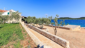 Ein Küsteneigentum mit einem Kiesweg, der zum Strand, einem Pool und einem Haus mit rotem Dach führt.