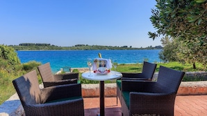 Ein Tisch mit Korbstühlen und einer Champagnerflasche, mit Blick auf ein Gewässer.