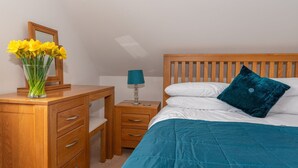 Un dormitorio con cama de madera, una mesita de noche, un escritorio y un espejo.