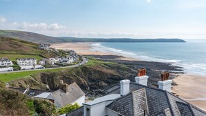 A coastal town with houses along the beach, rocky cliffs, and a clear view of the sea.