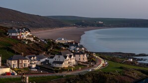 A coastal town with houses along the beach, a road curving through the town, and a view of the sea.