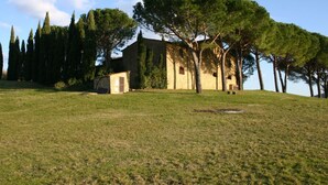 Un campo erboso con un edificio in pietra e alberi.