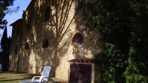 Un edificio in pietra con finestre ad arco e un ingresso chiuso da un cancello.