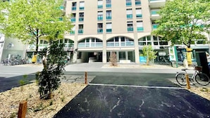 A modern building with a central entrance, multiple floors, and a parking area with bicycles. - Cozy Apartment Downtown Annecy, Parking, Wi-Fi Included (Annecy)