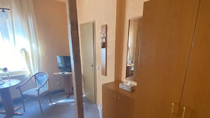 A room with a wooden wardrobe, a desk with a chair, a television, and a window with curtains. - Thüringer Hof (Ziegenrueck)