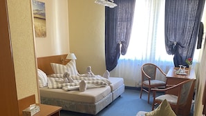 A hotel room with a bed, a sofa, a dining table with chairs, and a window with curtains. - Thüringer Hof (Ziegenrueck)