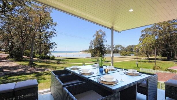 Un espace extérieur aménagé pour prendre les repas, avec vue sur la plage et l’océan.