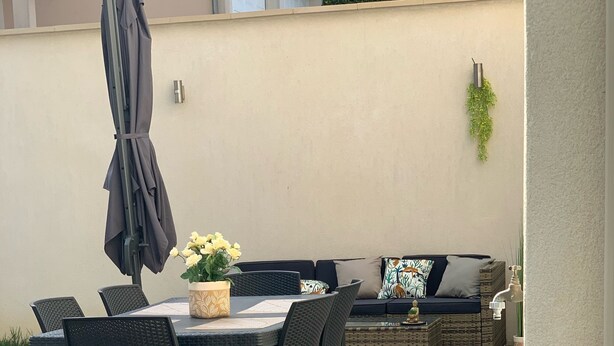 Eine Terrasse im Freien mit einem Esstisch und Stühlen, einer Couch und einem Blumentopf.