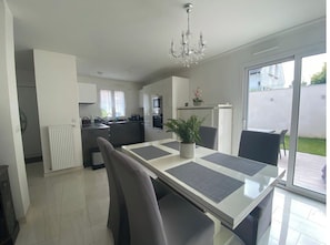 Una cocina moderna con armarios blancos, una mesa de comedor con individuales grises y una araña.