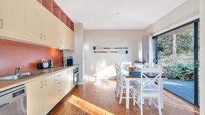 A modern kitchen with a dining area, wooden flooring, and a view of the outdoors.