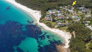 An aerial view of a coastal area with a beach, residential buildings, and a marked location.