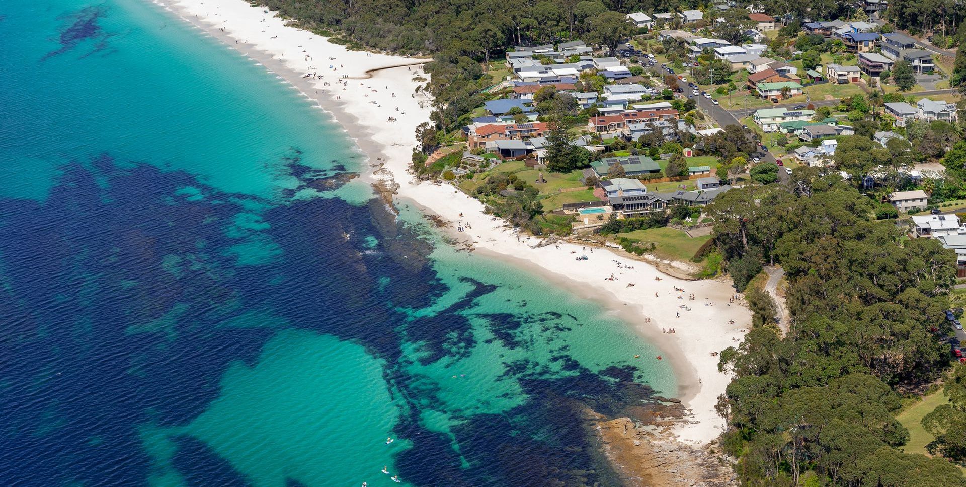 Vue aérienne d’une zone côtière comprenant une plage, des immeubles résidentiels et un point de repère clairement identifiable.