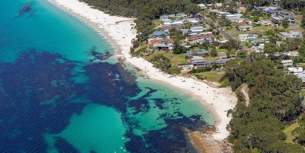 An aerial view of a coastal area with a beach, residential buildings, and a marked location.