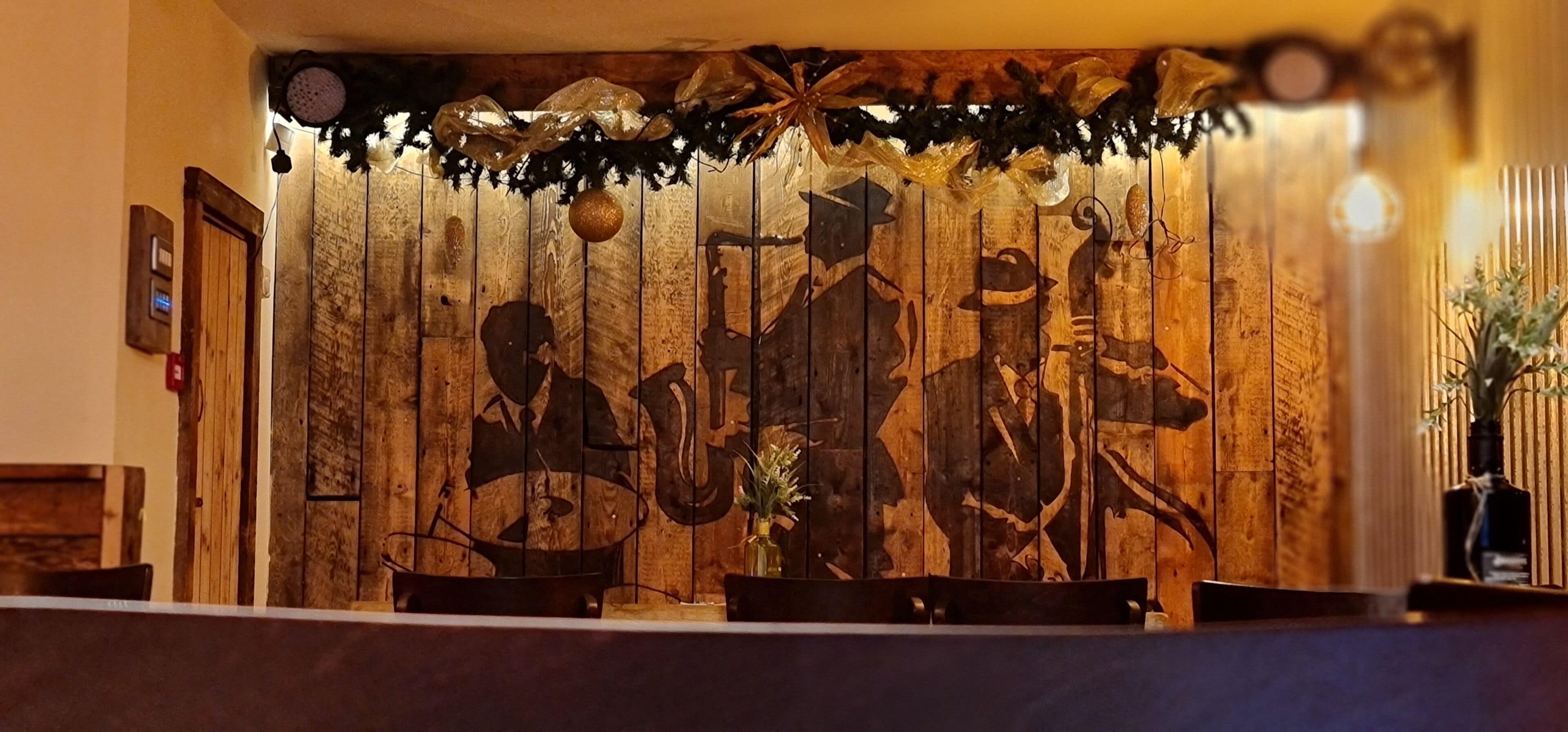 Eine Holzwand mit eingekerbten Figuren, einer Tür und einem Empfangstisch.