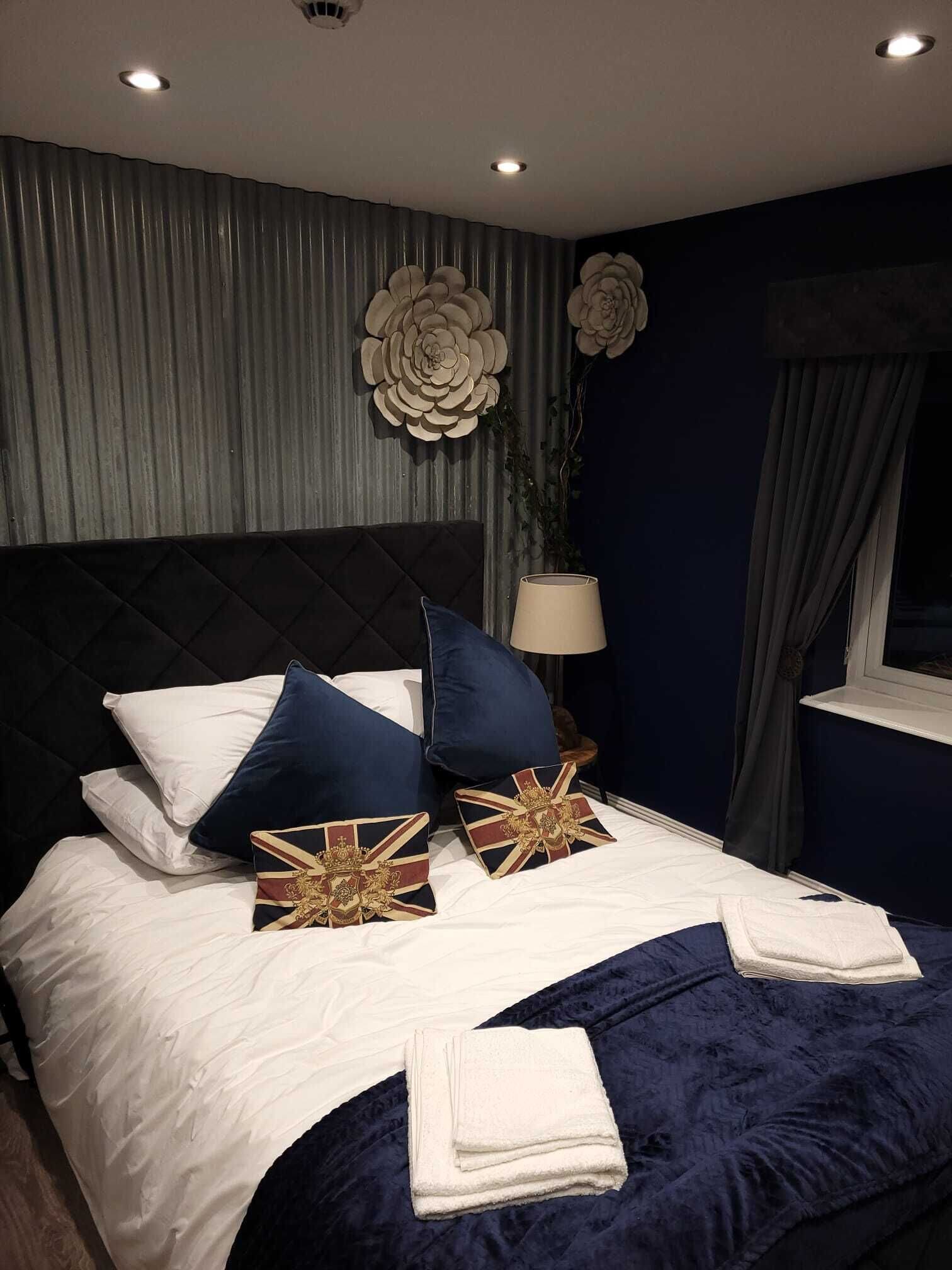 A neatly made bed with pillows, a lamp, and a window with curtains.