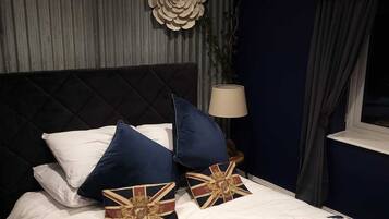 A neatly made bed with pillows, a lamp, and a window with curtains.