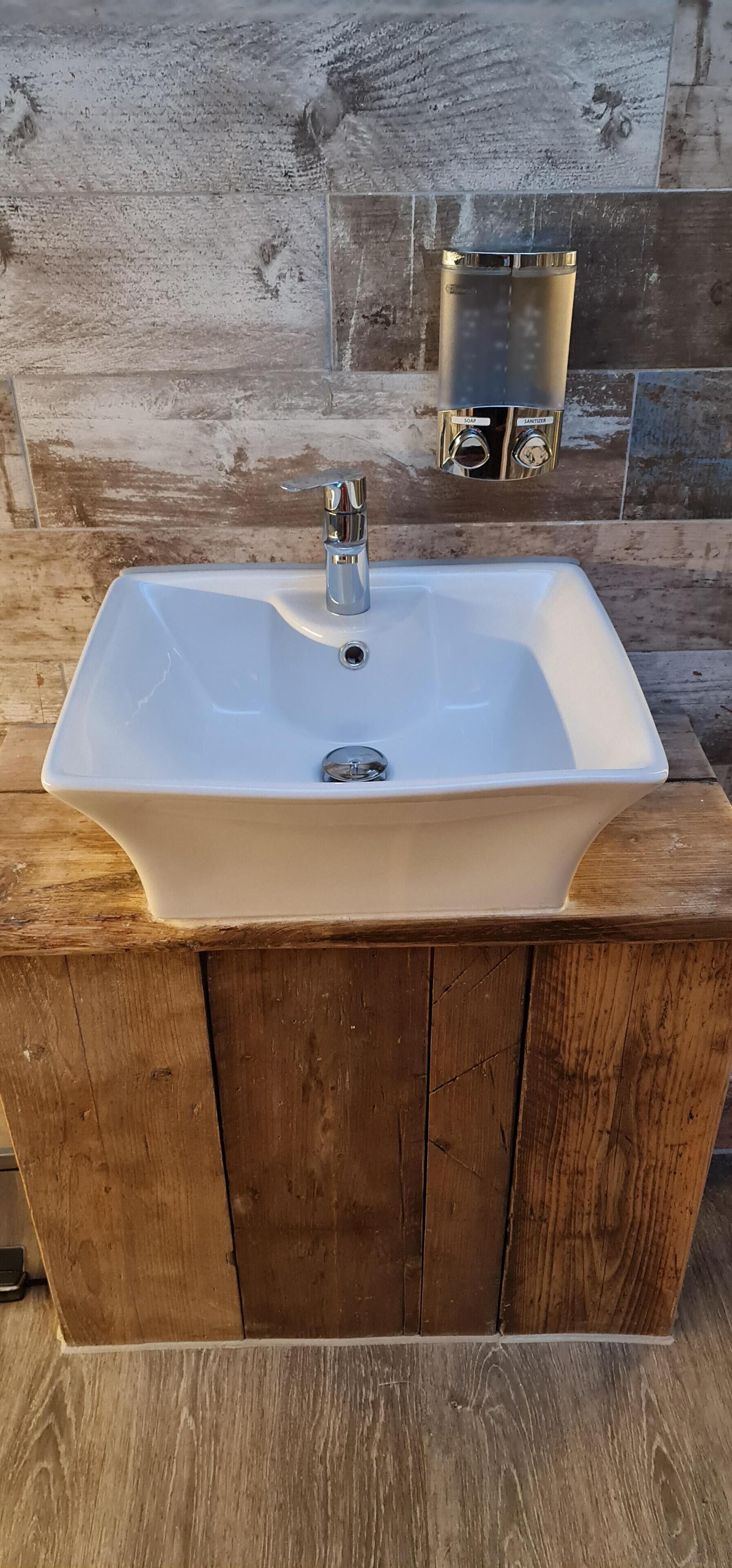 A white rectangular sink with a single faucet on a wooden vanity.