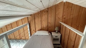 Una cama individual en una habitación con paredes de madera y techo inclinado.