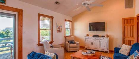A spacious living room with a ceiling fan, a large TV, and a wooden cabinet.