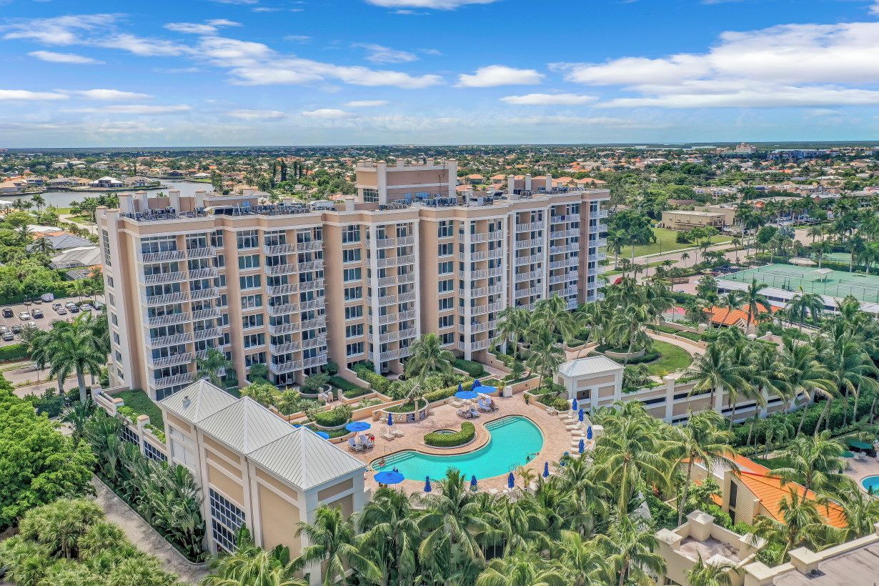 A multi-story hotel with a central pool surrounded by palm trees and lounge areas.