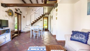 A spacious living area with a staircase, a dining table, and a sofa.