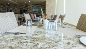 A restaurant setting with a marble countertop, neatly arranged dining tables, and chairs. - Lodge by Eagles (Sekondi-Takoradi)